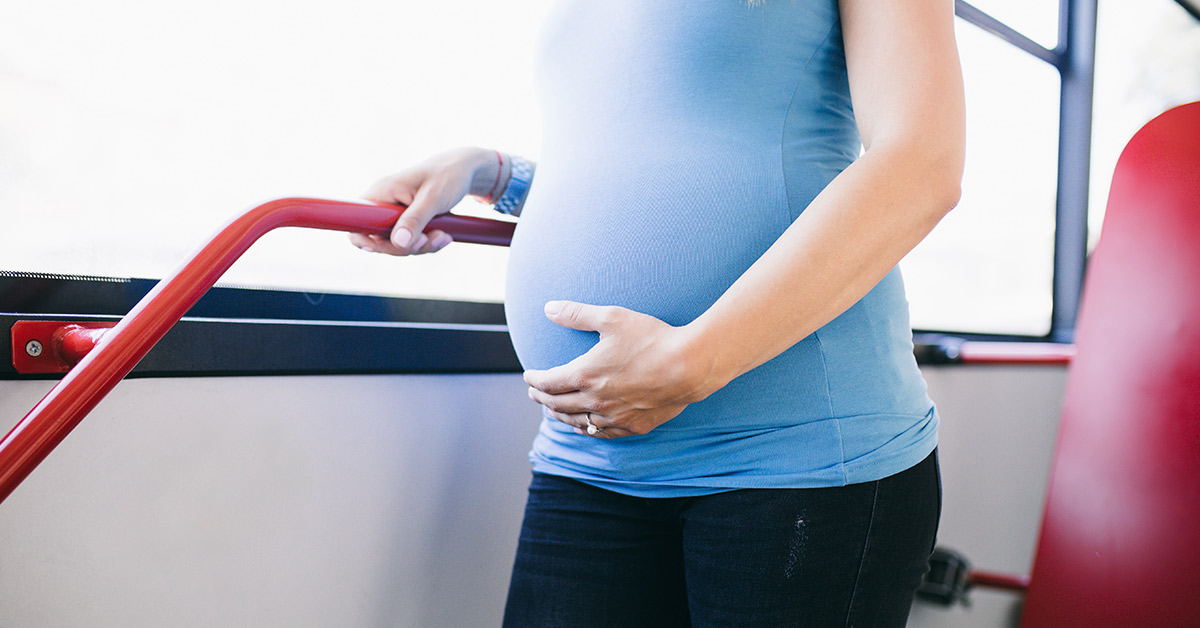 pregnant woman standing on bus