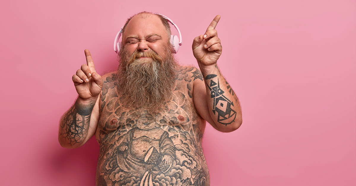 tattoed man with headphones on enjoying music