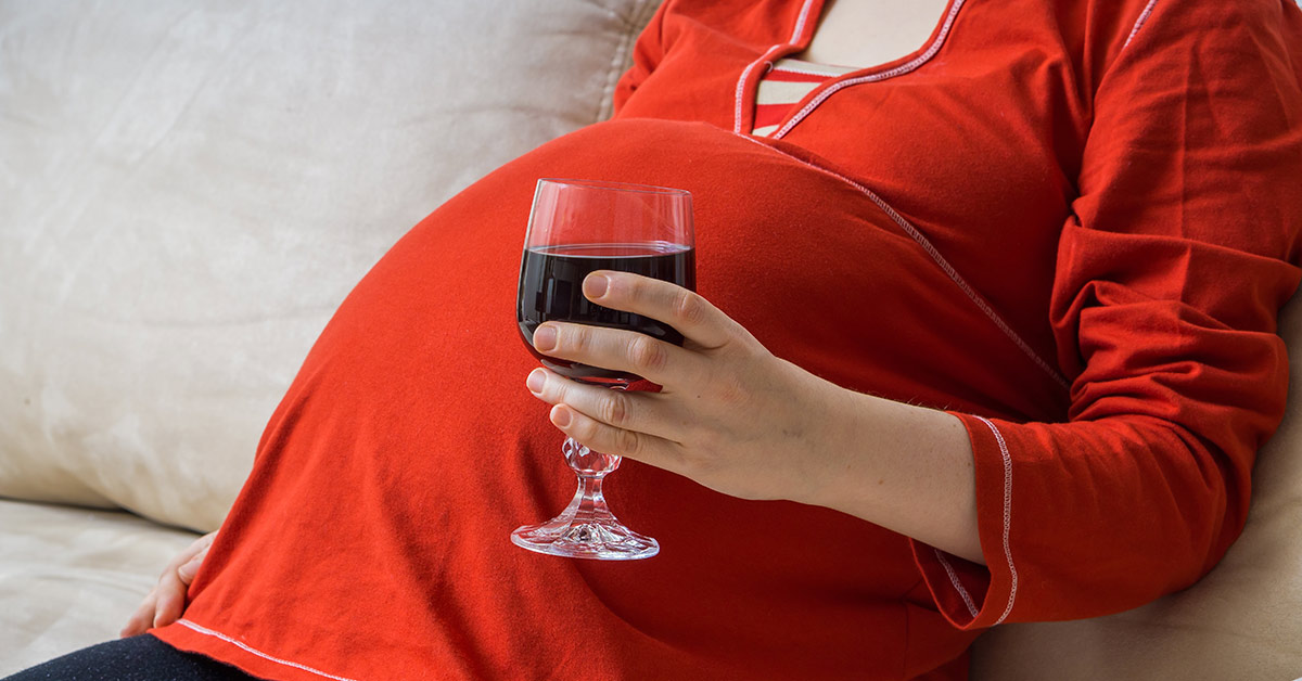 pregnant woman holding glass of red wine