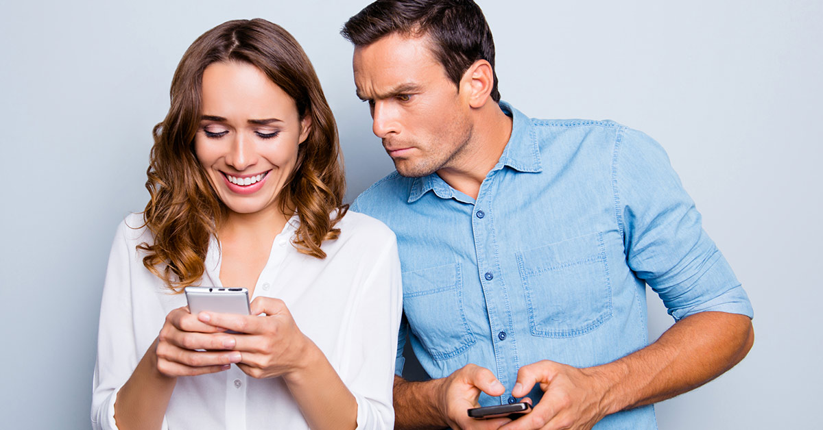 man staring over womansshould as she checks her phone
