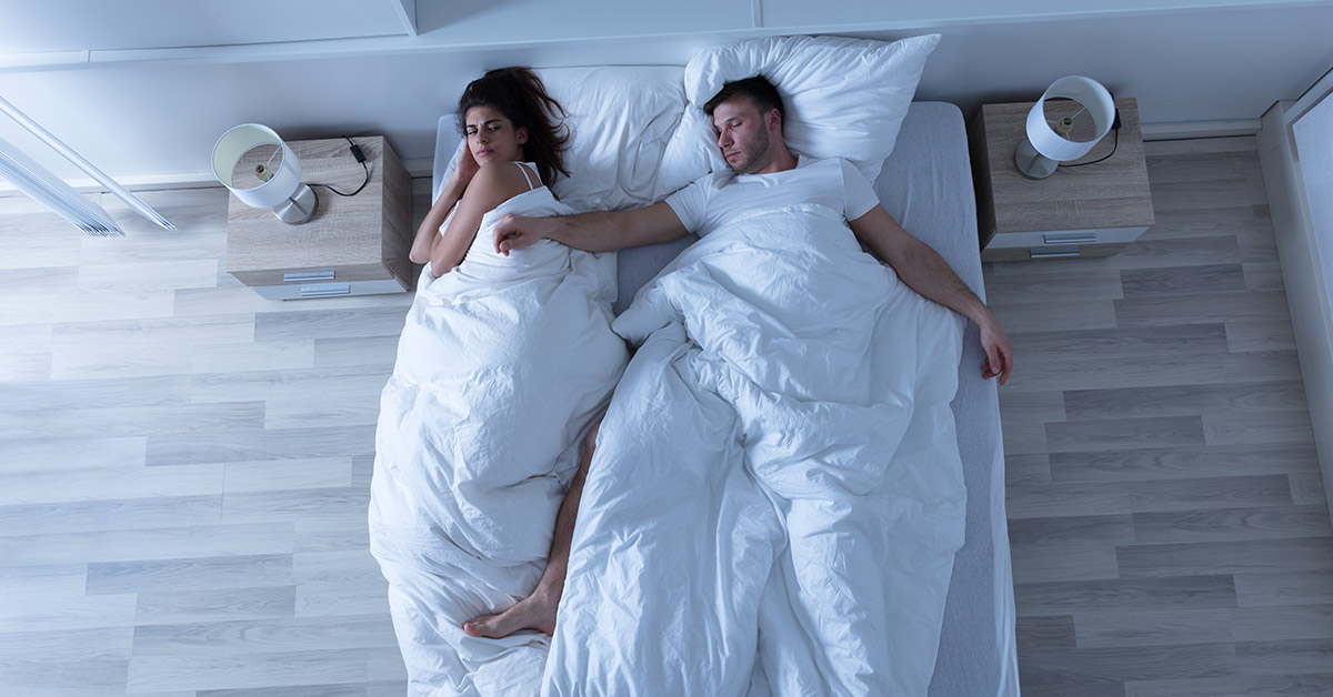 man sleeping spread out in bed with wife