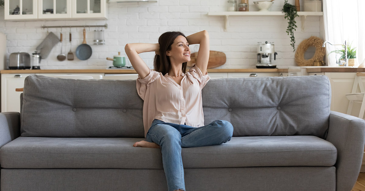 happy woman sitting on a grey couch