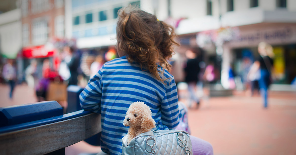 child sitting on park bench with stuffed toy