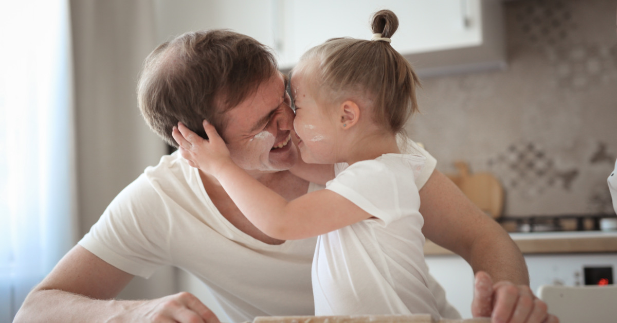 girl with down syndrome kissing her father
