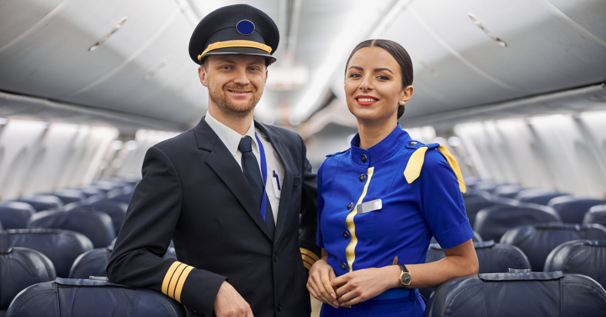 a pilot posing with a flight attendant in the passenger section of a plane