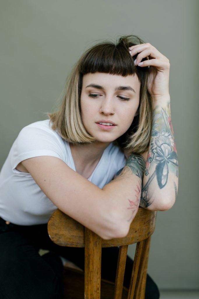 woman, smiling, chair, tattoos, bangs