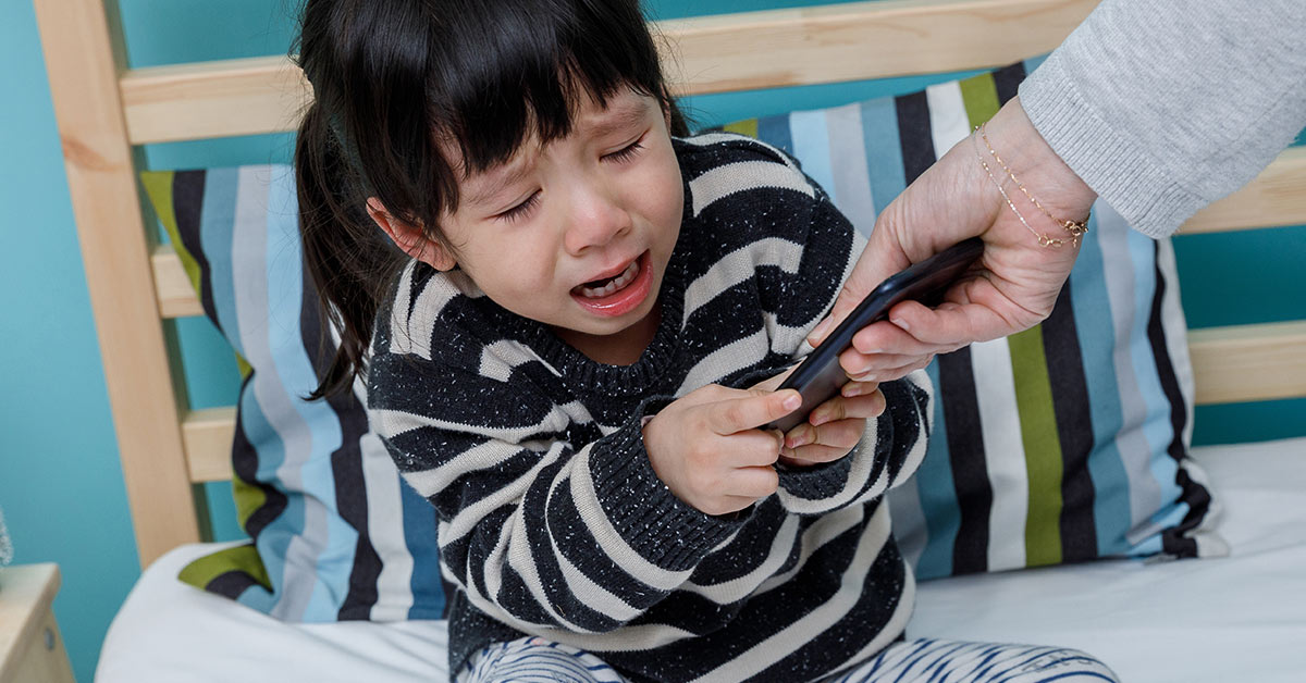 girl crying because of handheld device