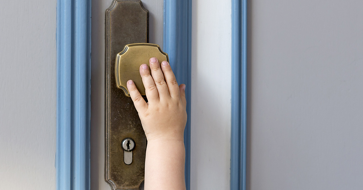 a child's hand reaching for a door handle
