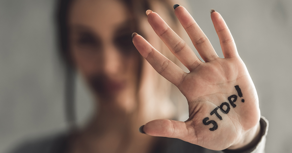 female extending hand with "STOP" written on the palm