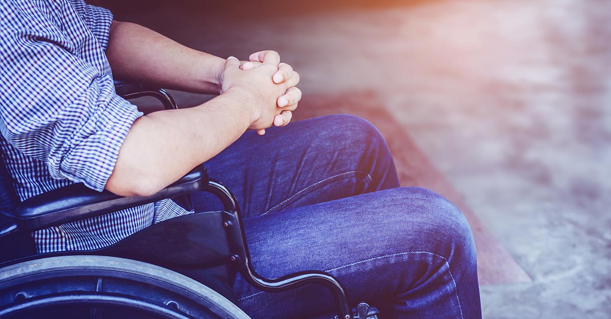 wheelchair bound person with hands clasped in lap