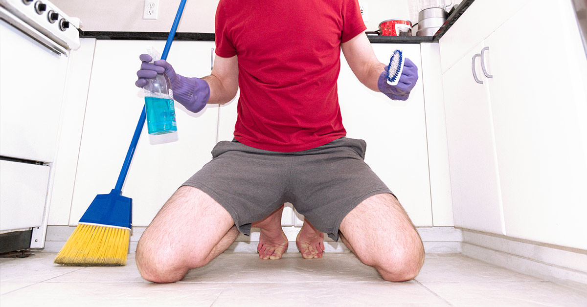 man on knees doing chores in kitchen