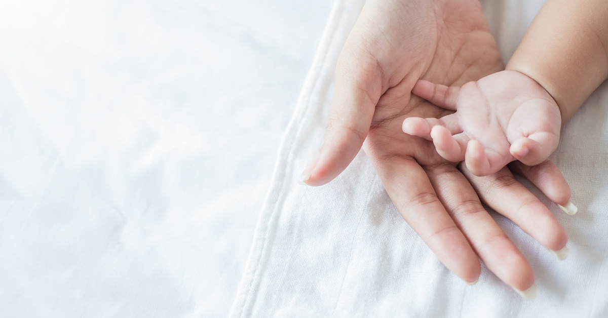 infant hand resting in parent's
