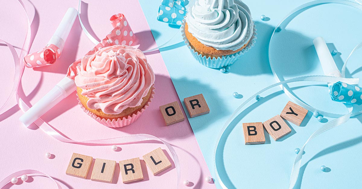 pink and blue cupcakes on a table with square wooden pieces spelling out "Girl or Boy"