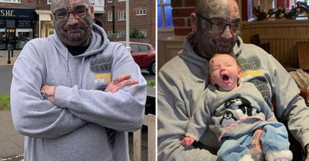 man with face tattoos holding child