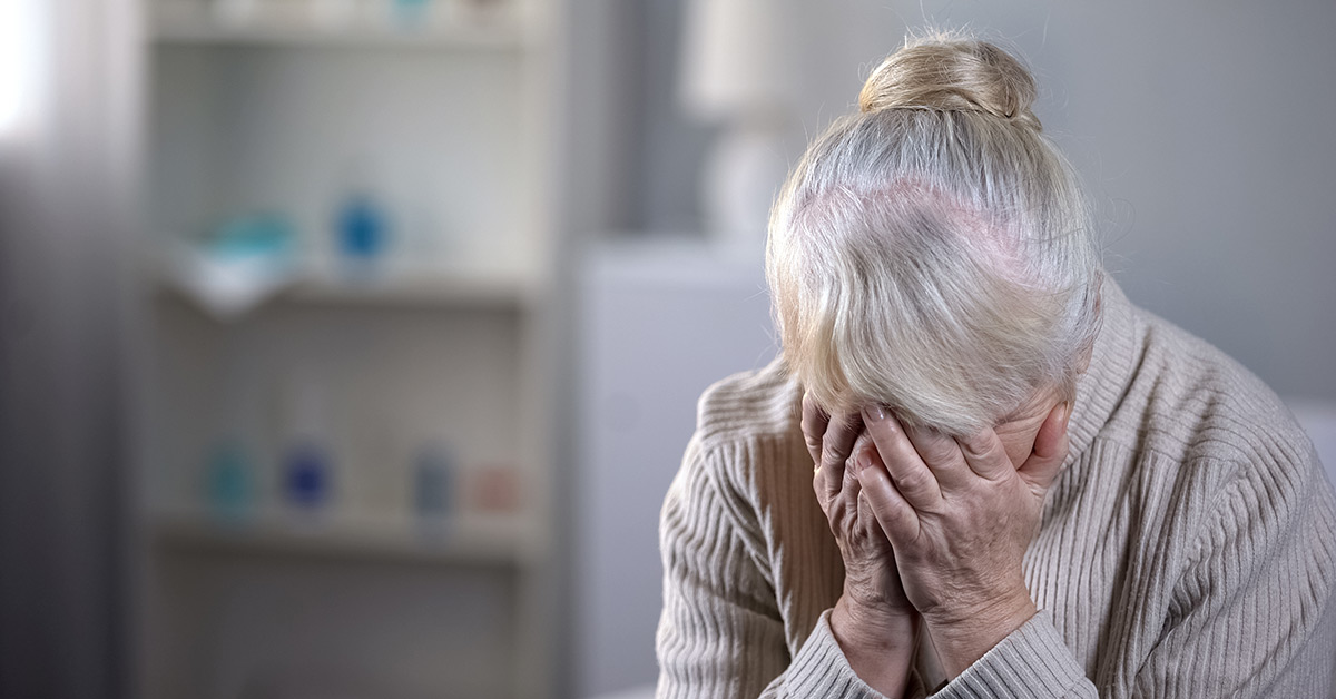 elderly woman crying with face in palms