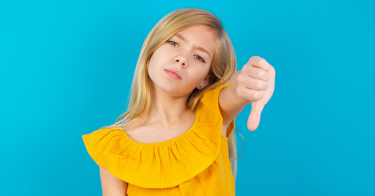 girl wearing yellow blouse giving one thumb down