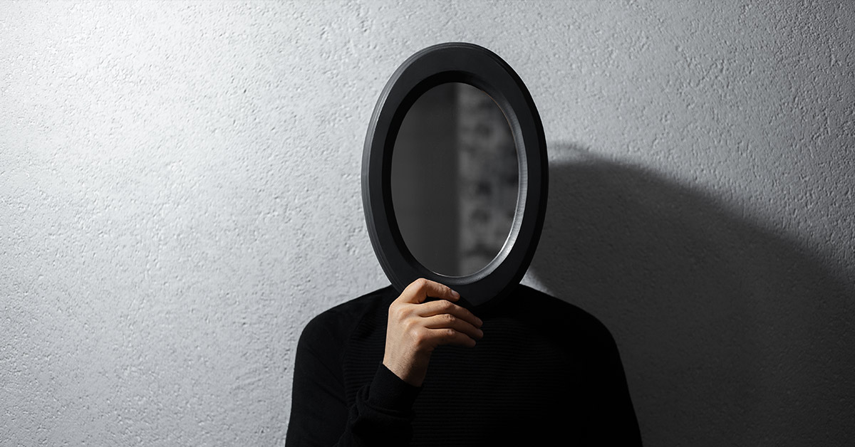 person in black placing a mirror over their face