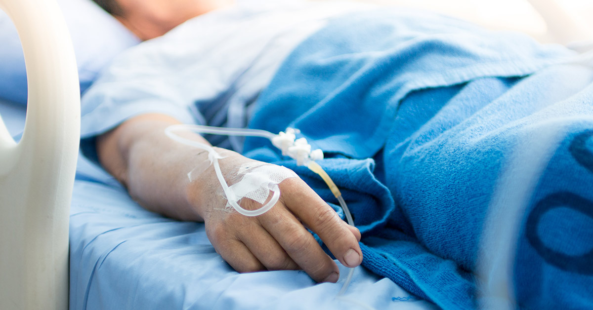 man laying on hospital bed with IV in hand