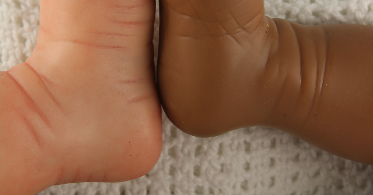 infant feet pressed together, one black (right), one white (left)