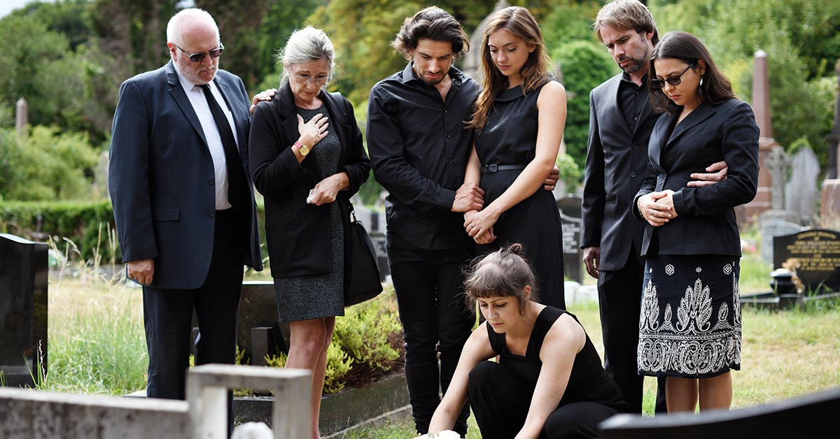 large family gathered in a cemetery for a funeral