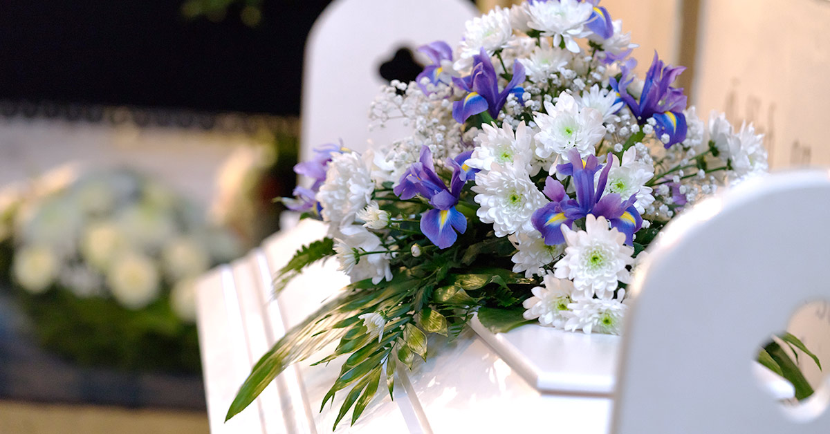 bouquet of white and purple flowers on top of a white casket