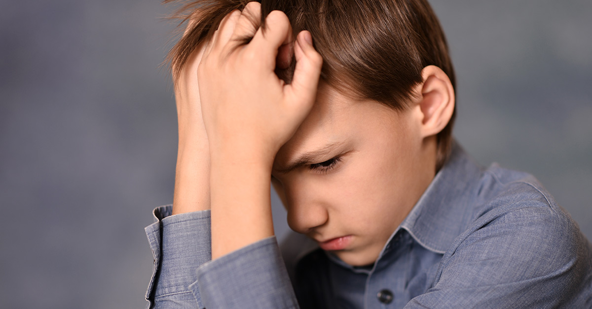 upset young boy with hands placed on forehead in frustration