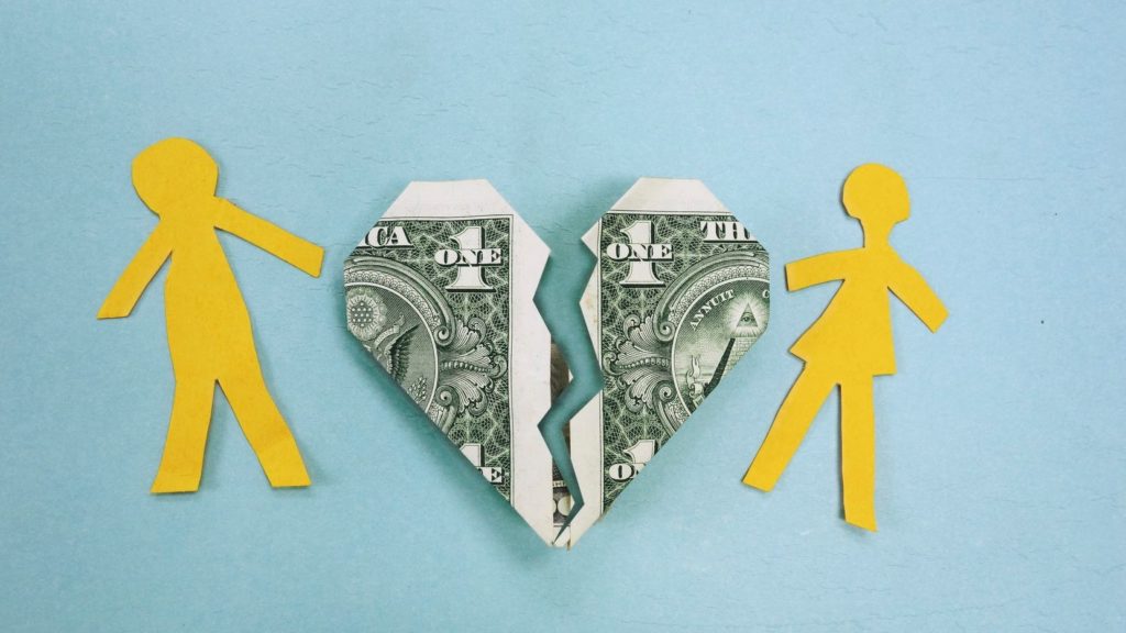heart with the pattern of an American one dollar bill being torn in half with two yellow paper cutouts of a man and a woman on each side 