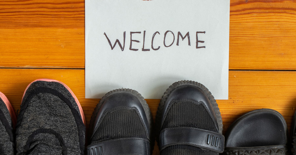 piece of paper with the word "welcome" written on it with black shoes placed in front of it on the floor