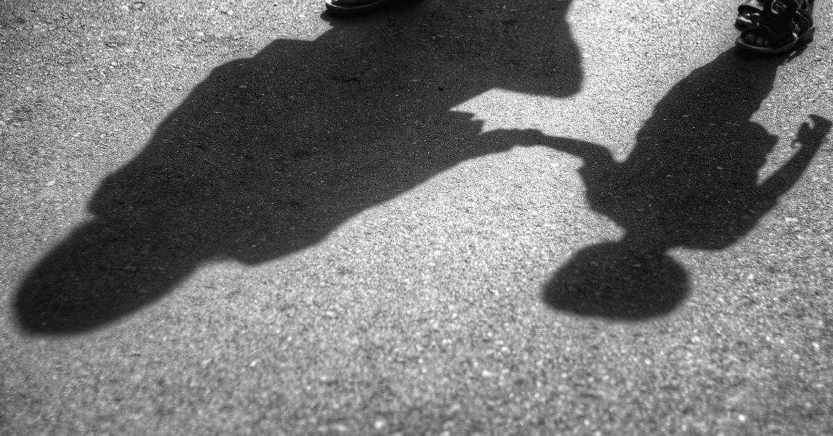 shadow of parent and child holding hands casted onto pavement