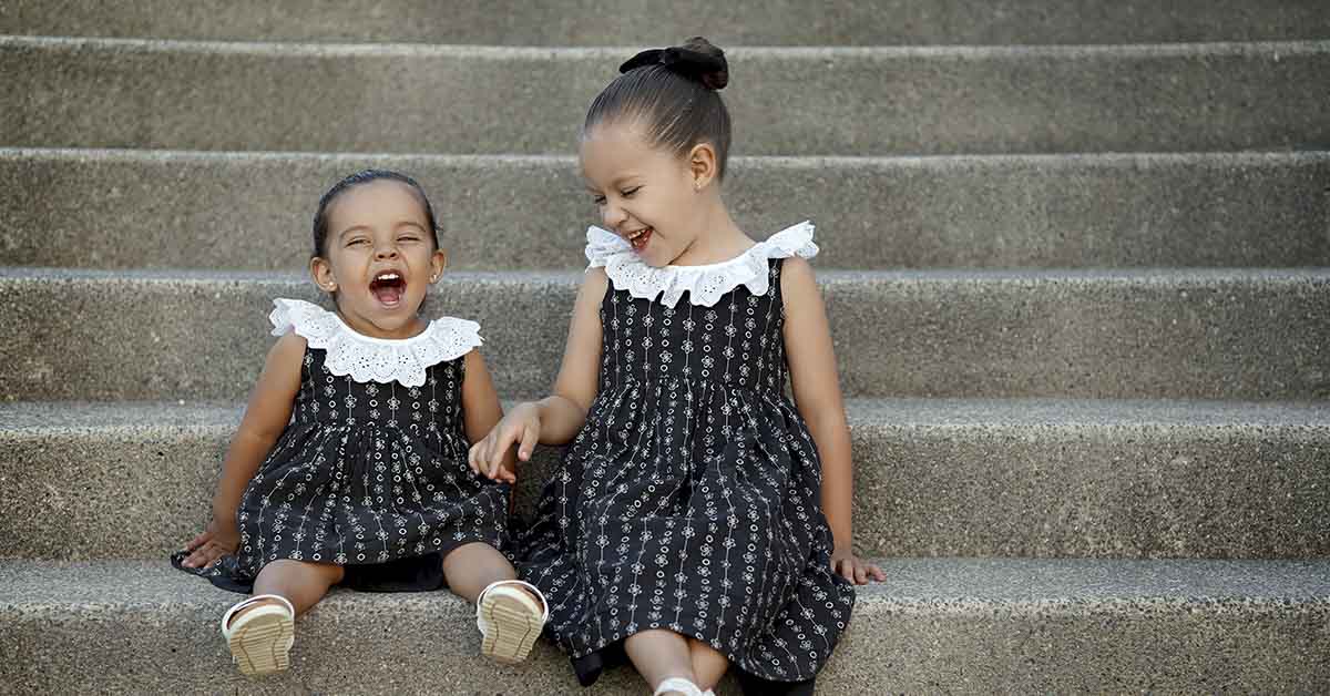 two young girls in dresses sitting on stairs