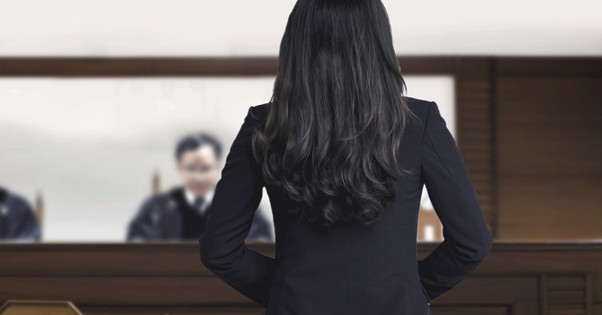 female lawyer standing in court with judge in background