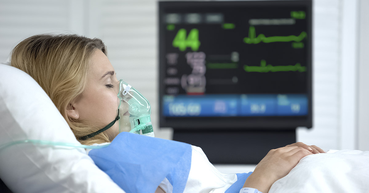 Woman in coma, heart rate falling on ecg monitor, intensive care hospital unit