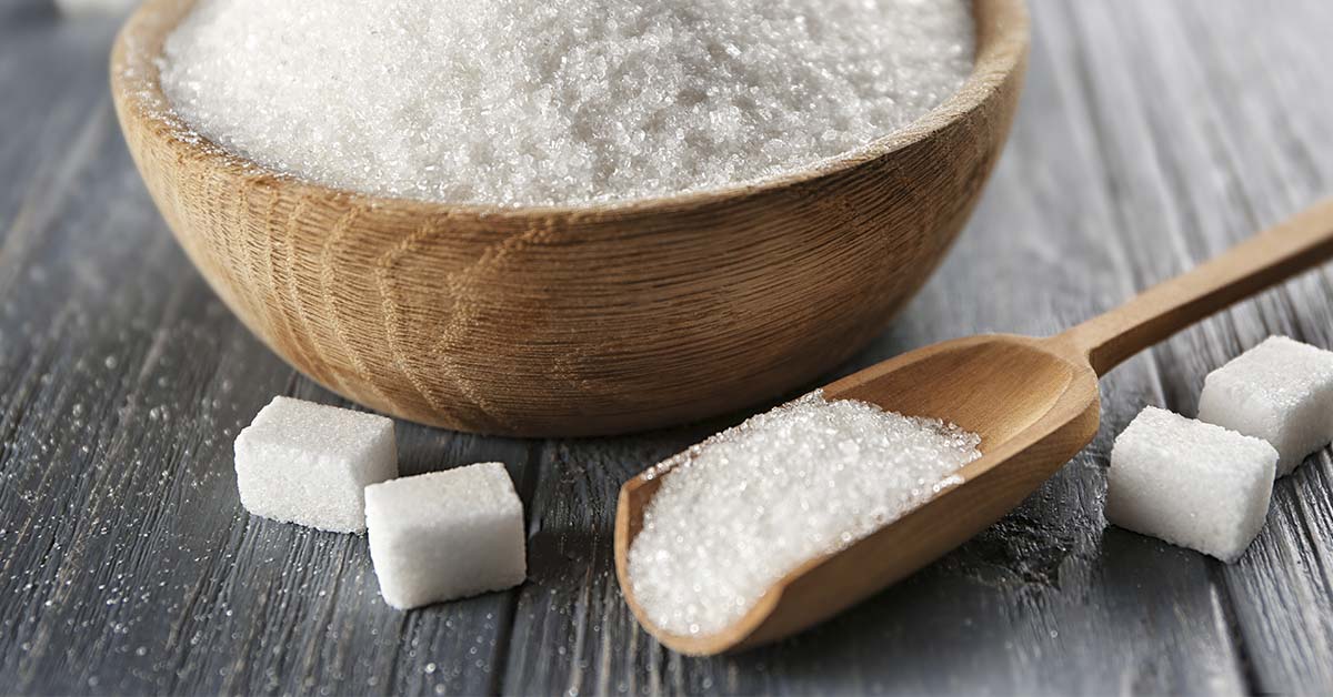 bowl of sugar with a cubes of sugar and a scoop placed outside of it