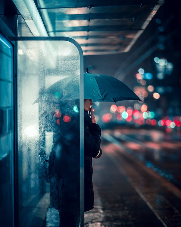 woman standing at a bus stop at night