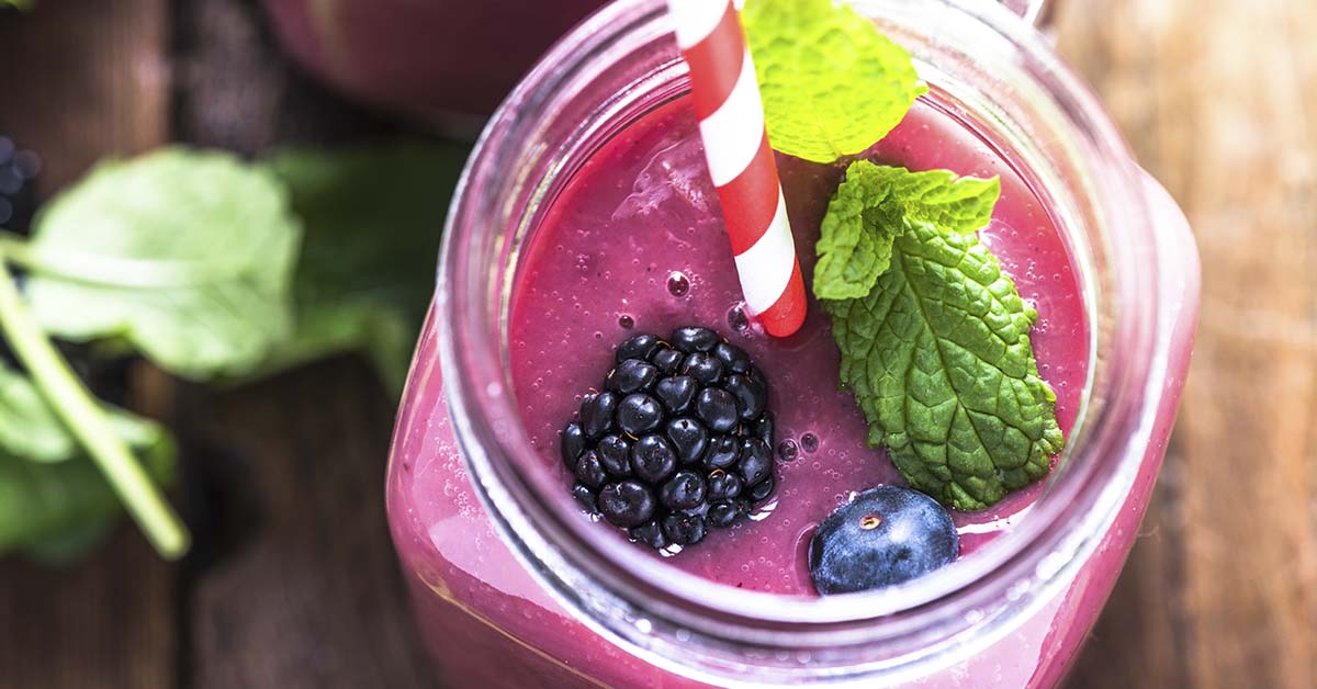 berry smoothy in mason jar topped with fruit and mind