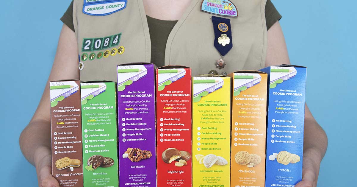 Girl Scouts member holding various types of their cookies