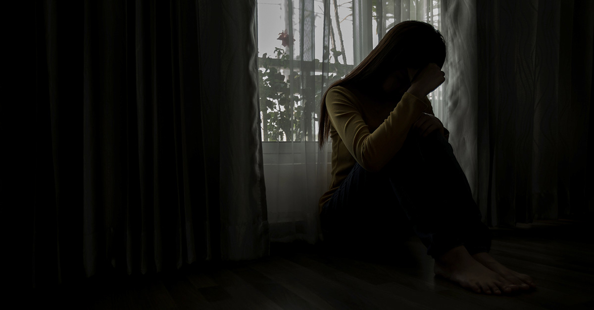 silhouette of sad woman sitting by a window