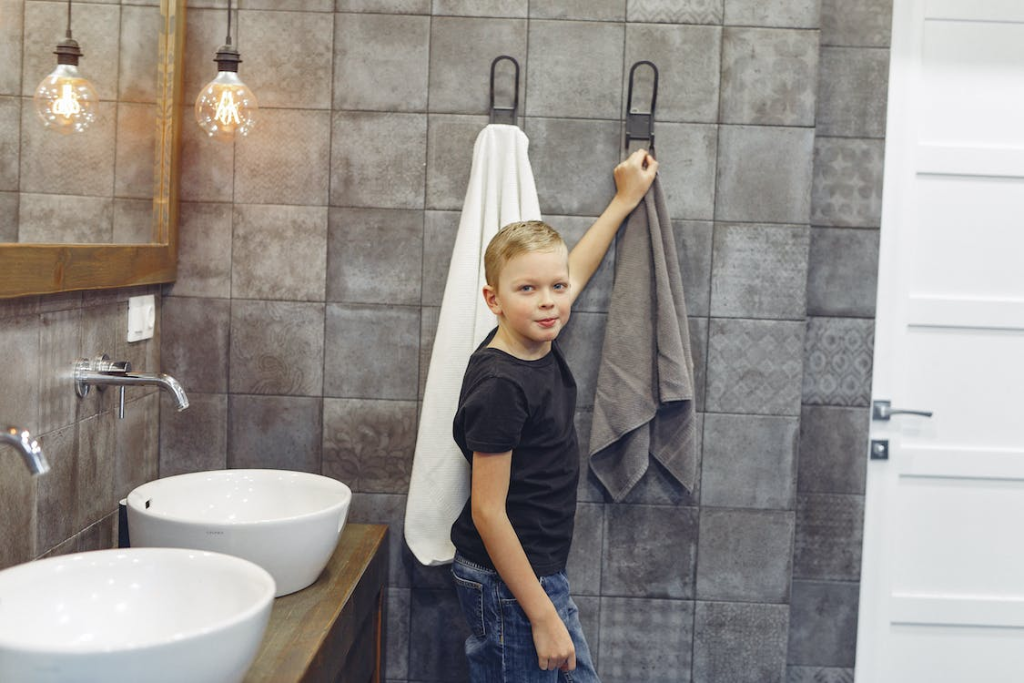 Small boy hanging up towel in bathroom
