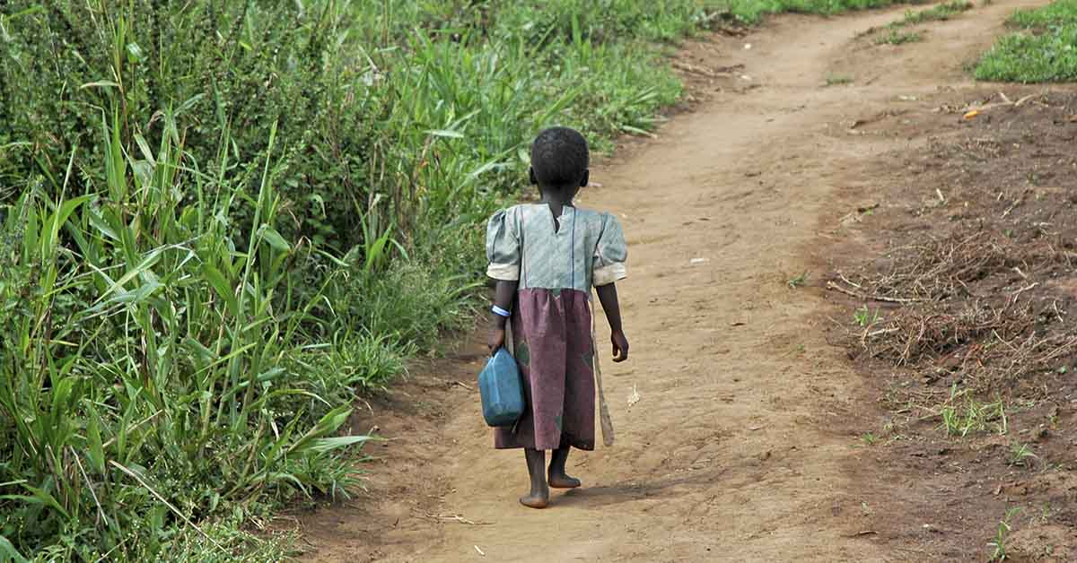 young African child walking down dirt road