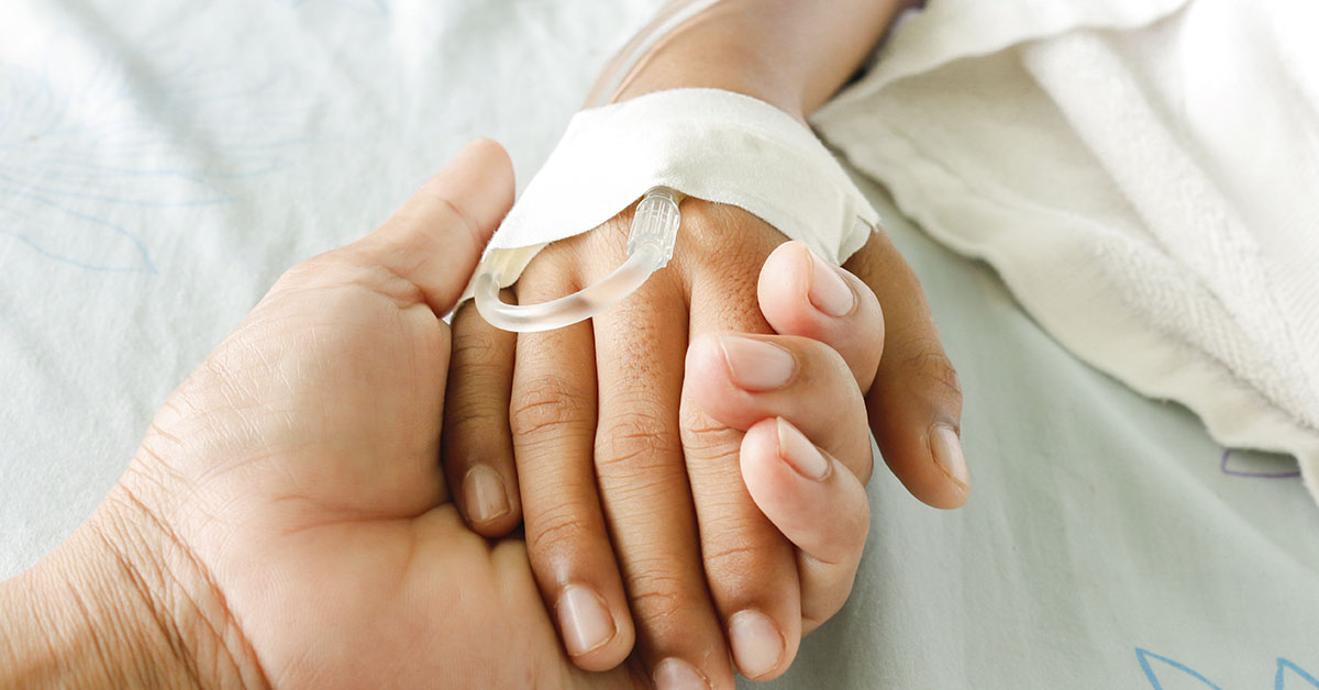 holding a hand with an IV in medical setting