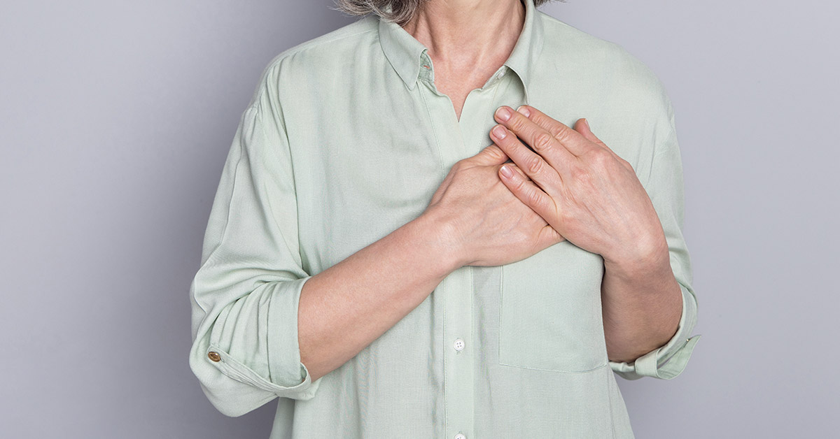 woman placing hands over left side of chest
