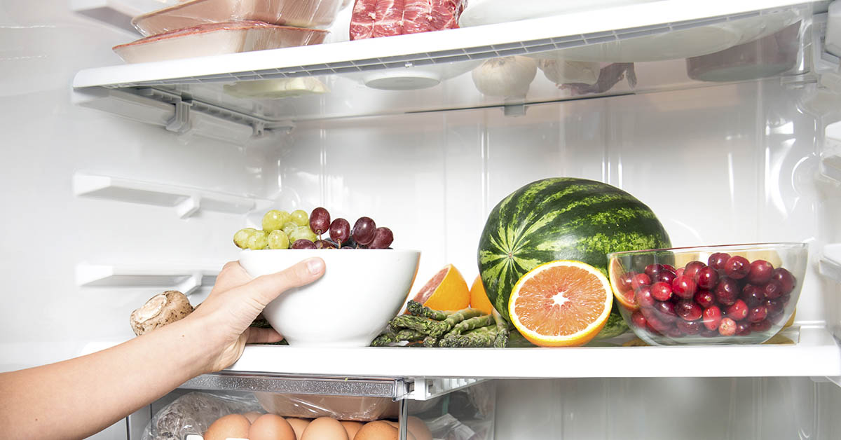 open fridge wih various foods on shelves including fruit, vegetables, meat and eggs