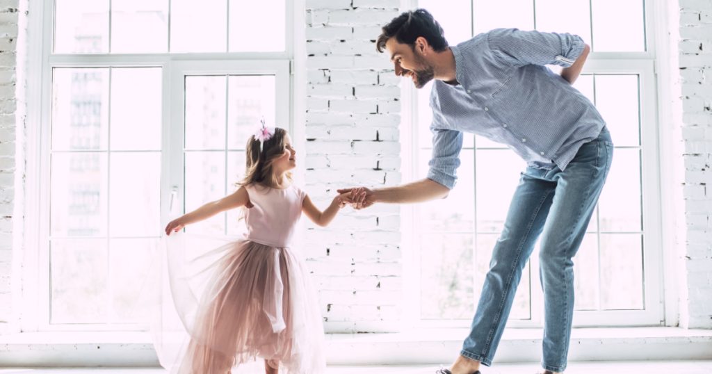 man is dancing at home with his little cute girl