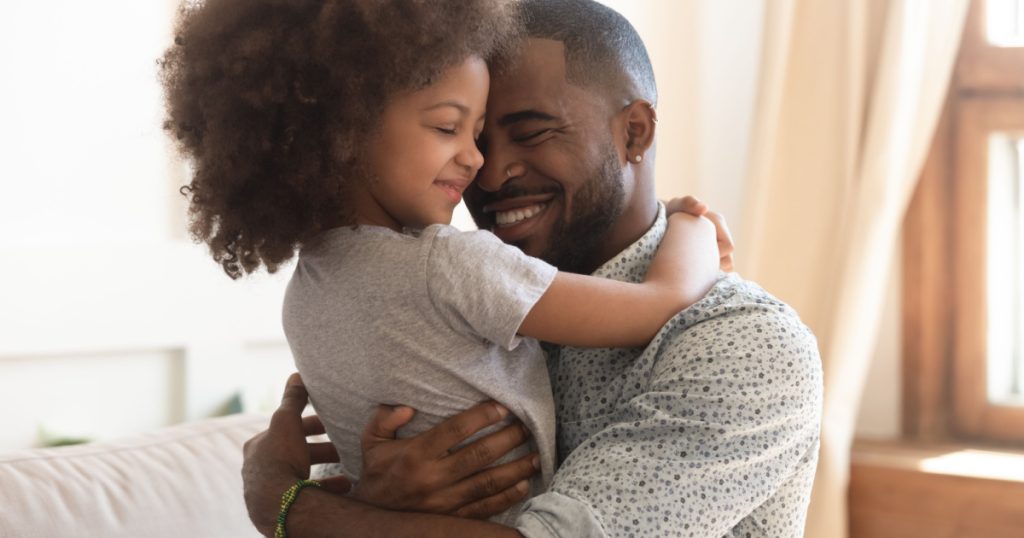 father hold embrace cute little child daughter, smiling black family mixed race daddy and small kid hugging cuddling enjoying time together at home