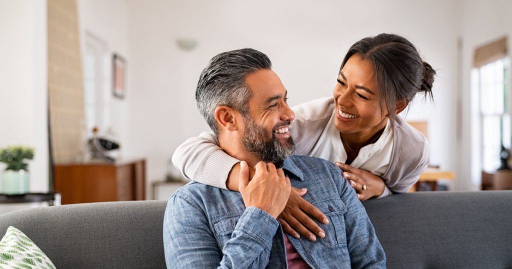 woman hugging her husband on the couch from behind in the living room