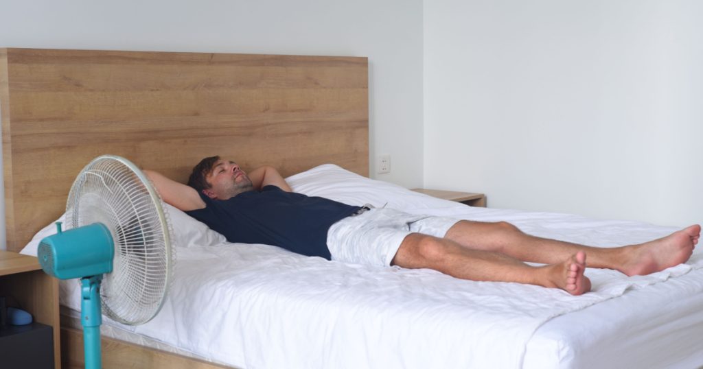 Man sleeping on a bed with fan 