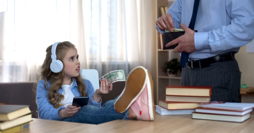 Busy father giving pocket money to little narcissitic children daughter with headphones
