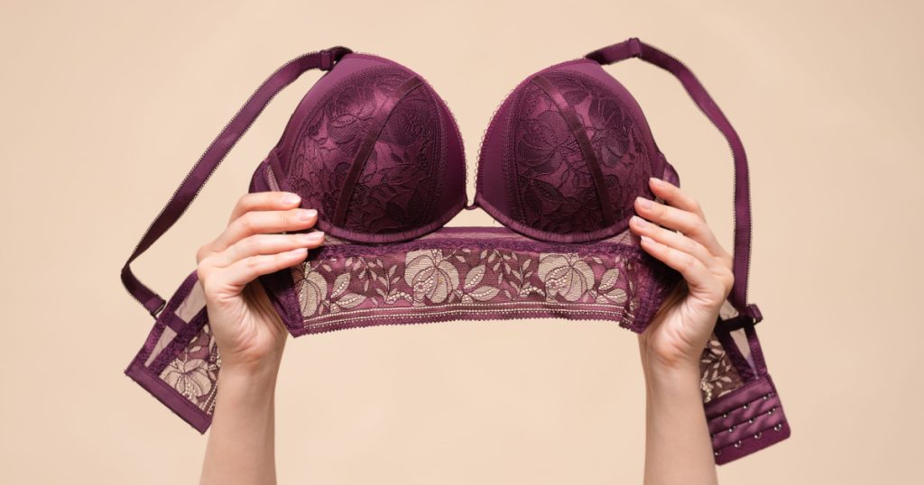Woman is showing a new bra in the hand above her head. Choosing a new bra concept.
