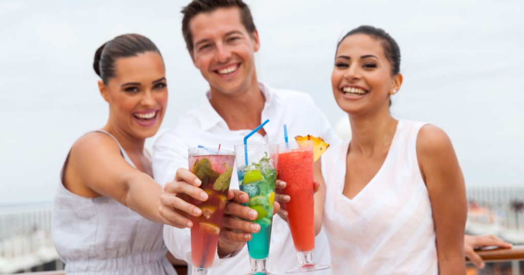 portrait of young people toasting with cocktail drinks on a cruise ship
