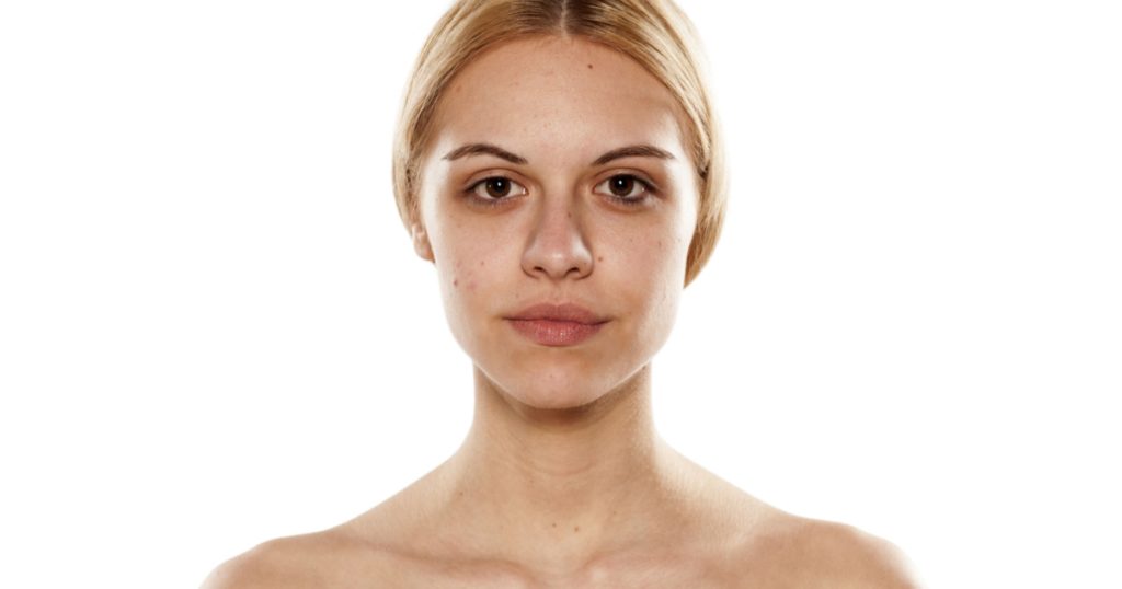 portrait of a young serious woman without makeup on a white background